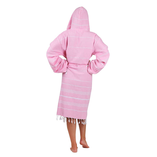 Rear view of the woman wearing Loom Legacy medium/large pink bathrobe showcasing the hood, white stripe pattern, and fringe detailing at the bottom.